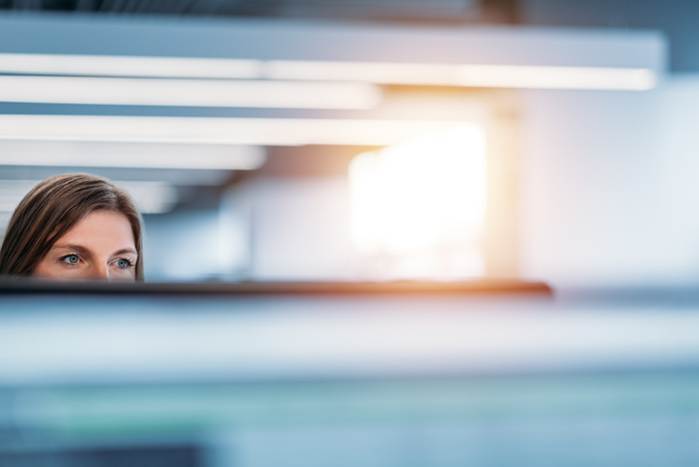 Woman looking over monitor at work - FMLA Retaliation